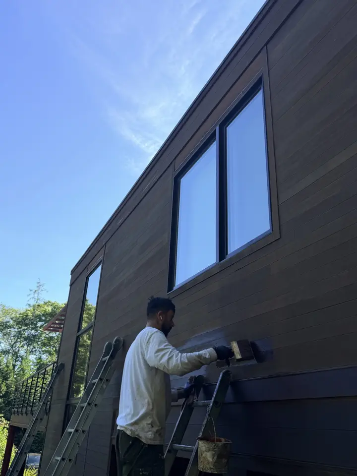 Crew member painting dark siding