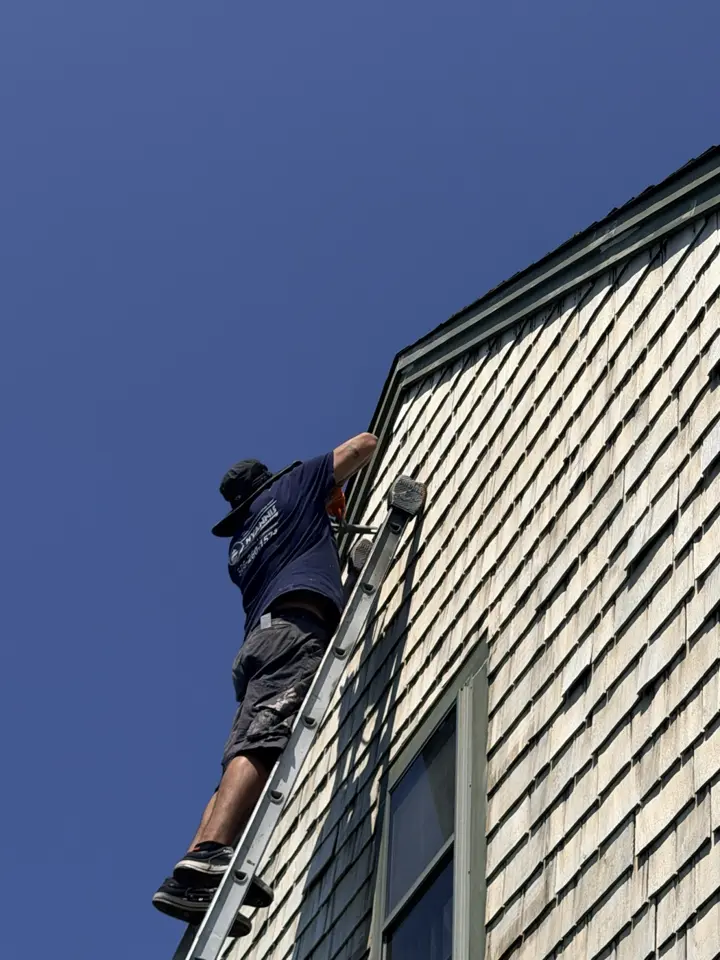 Crew member on a ladder at shingle siding