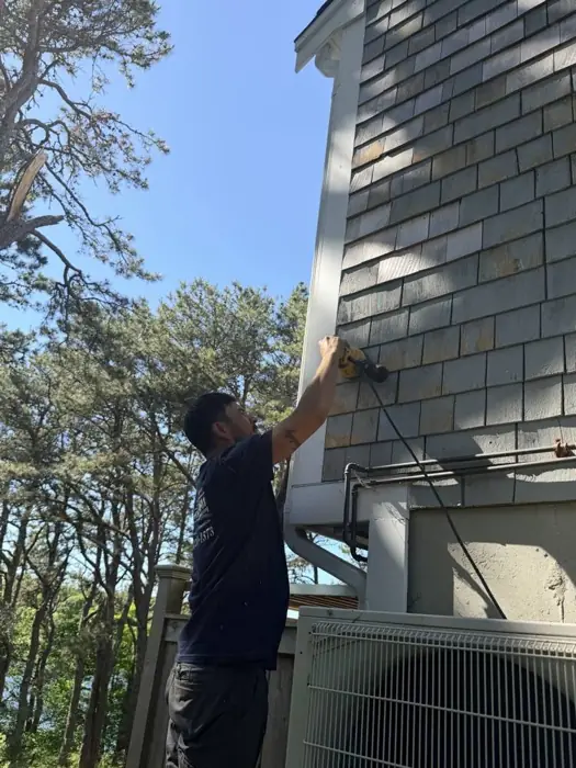 Crew member power washing cedar shingle siding