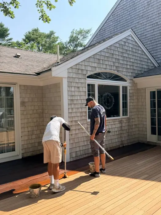 Two painters staining a deck